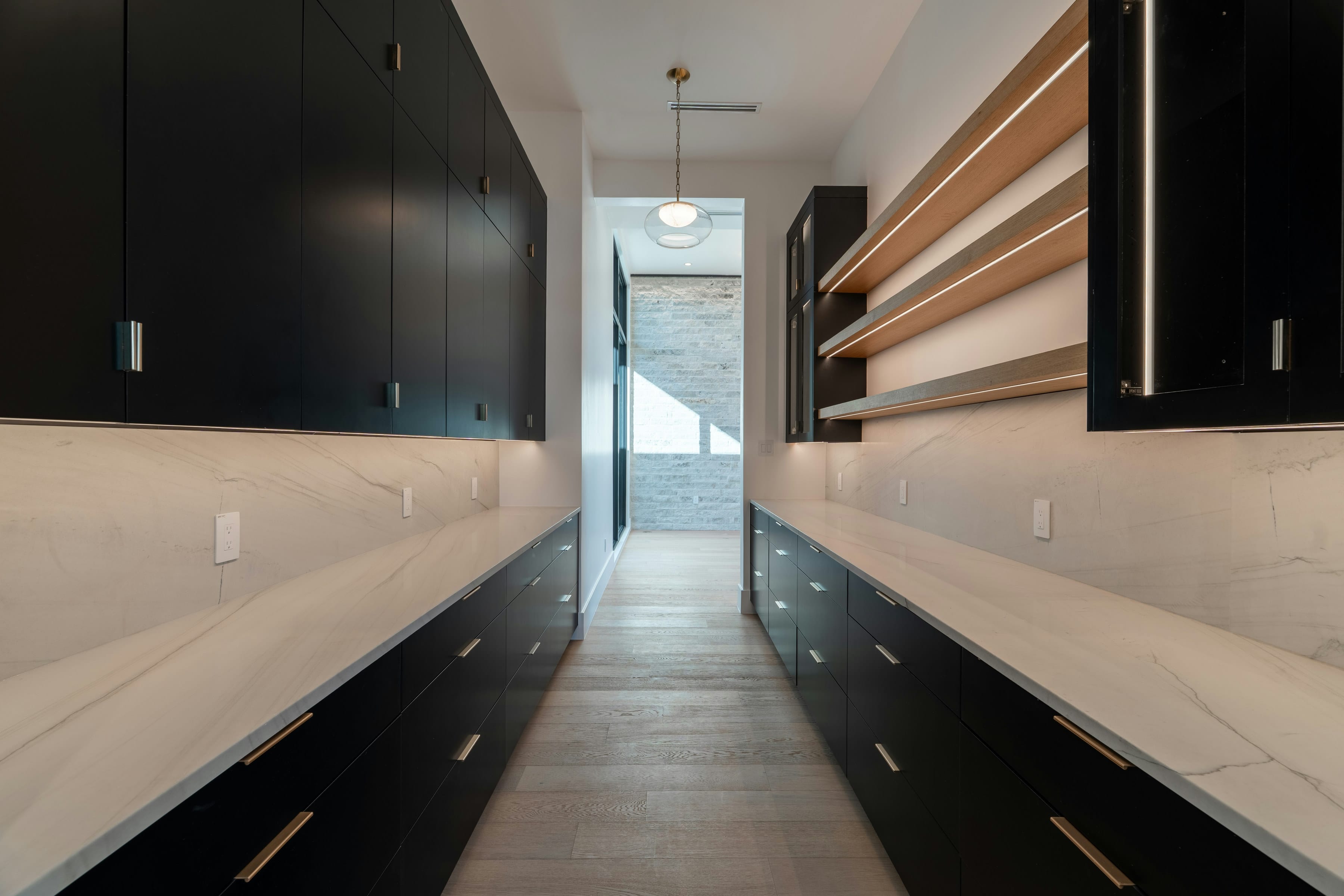 Long black butler pantry corridor with oak shelf and light worktops