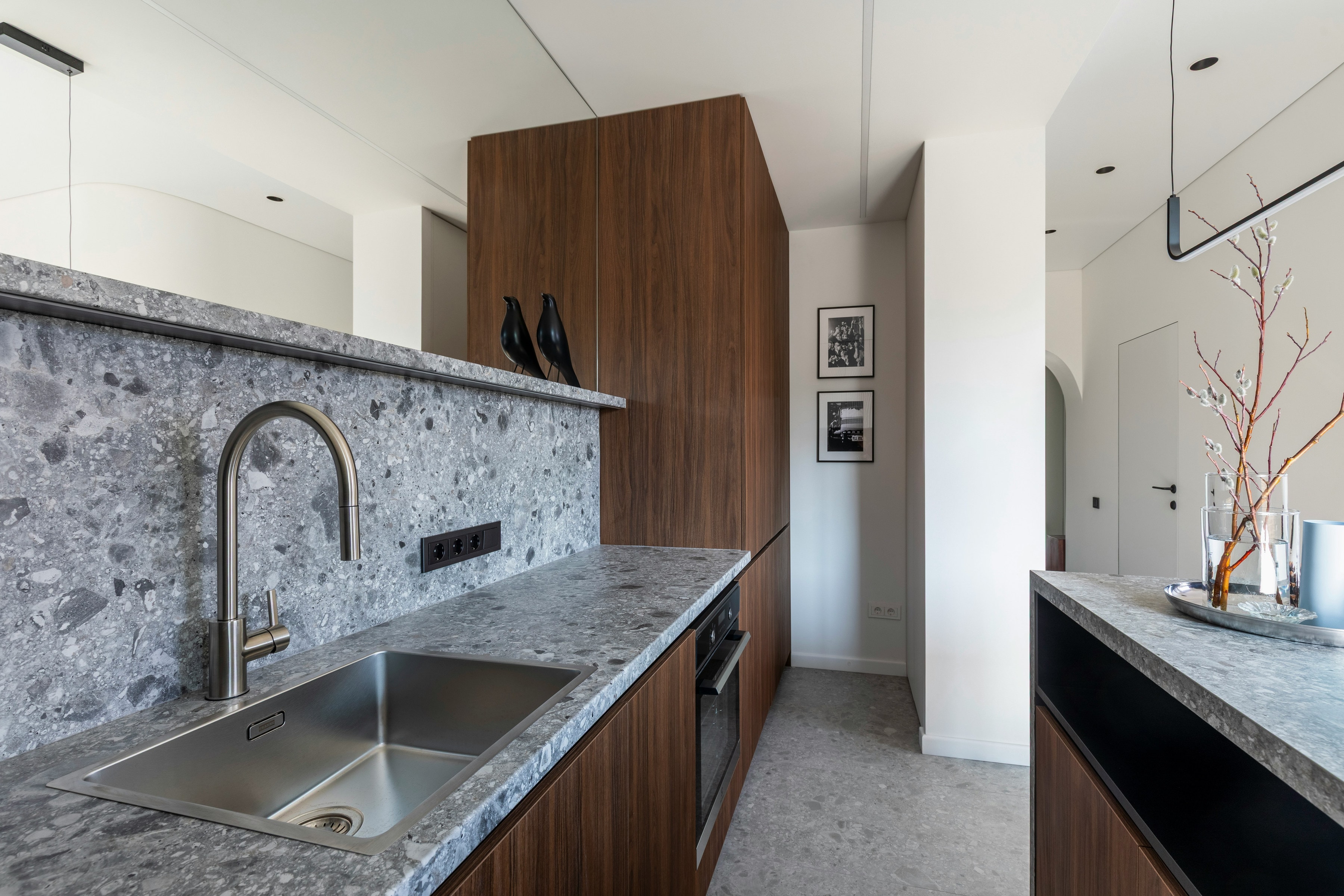 Narrow kitchen with terrazzo splashback, walnut tall unit and stainless steel sink