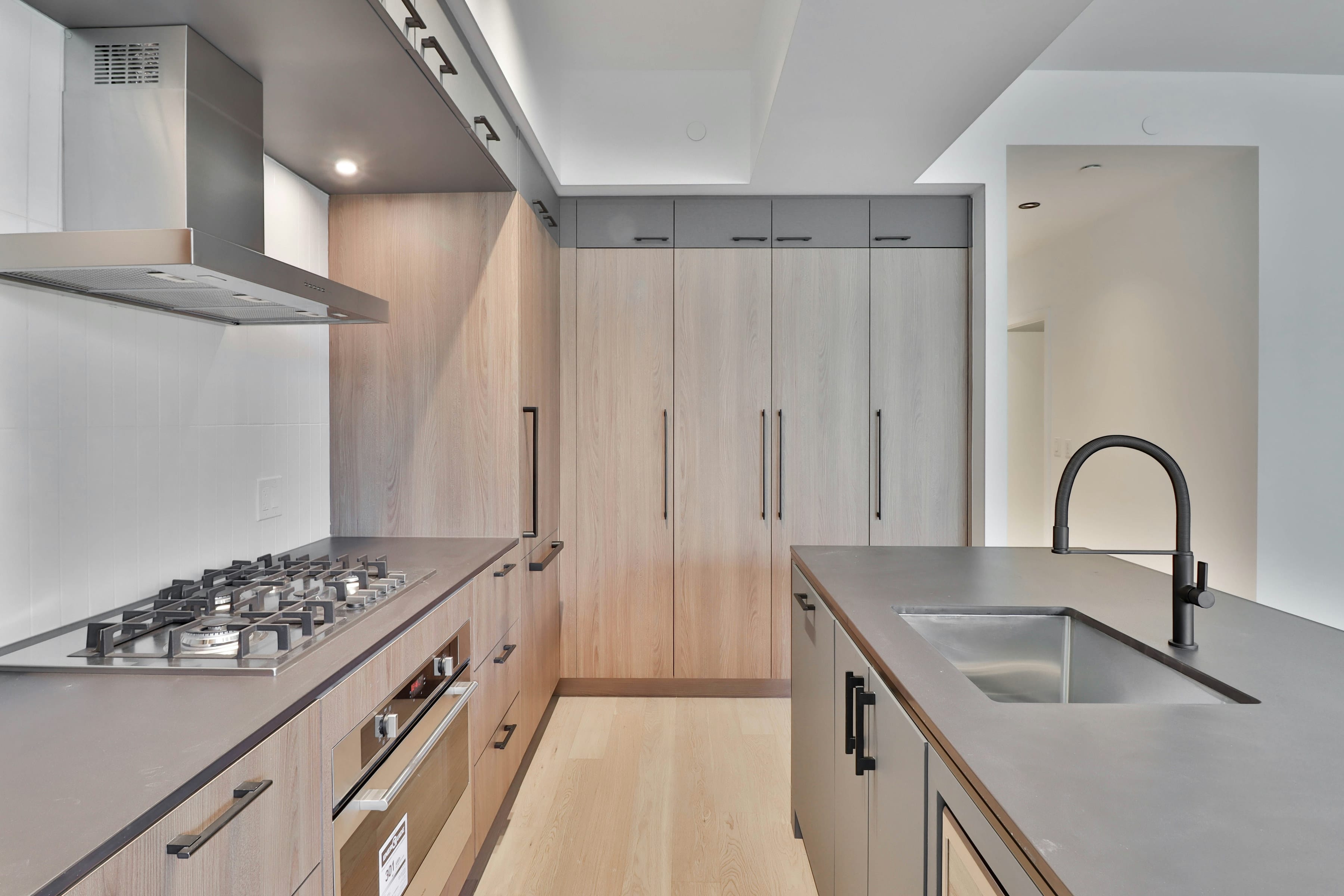 Slim galley kitchen with wood cabinets, gas hob and sink along one wall