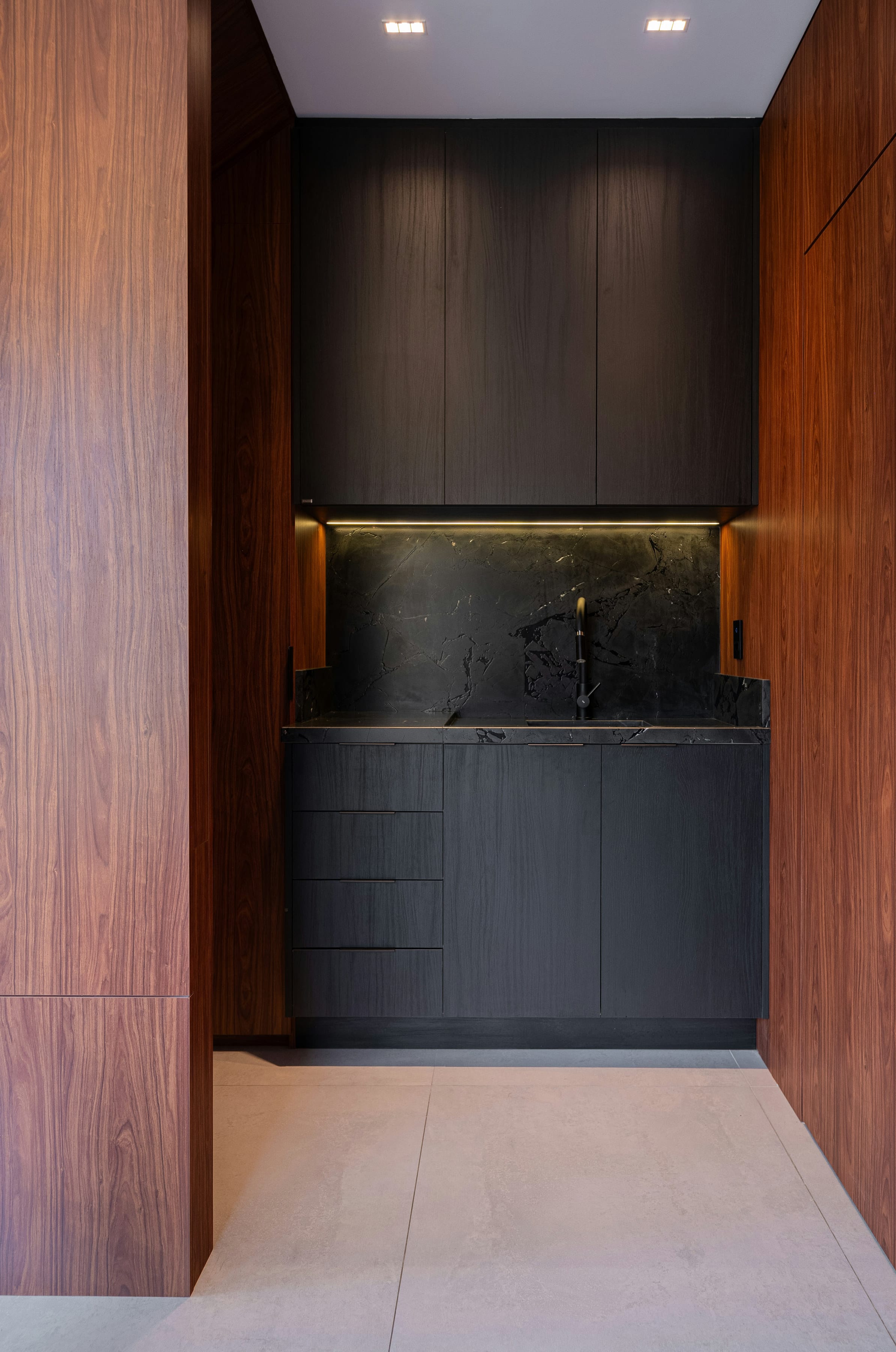 Walnut-framed black marble look niche with warm LED strip light
