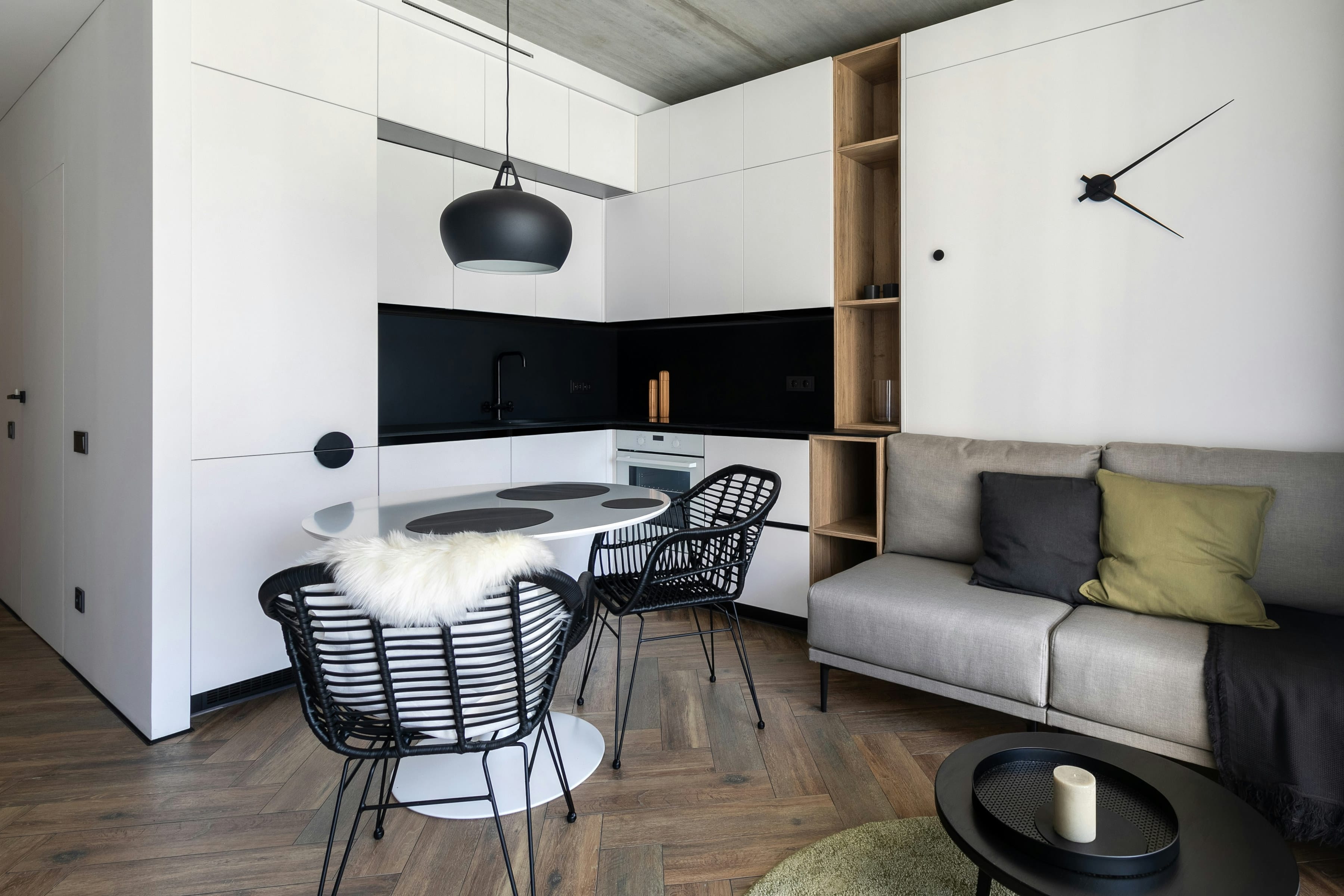Compact studio apartment with white cabinet wall hiding a corner kitchen beside a lounge