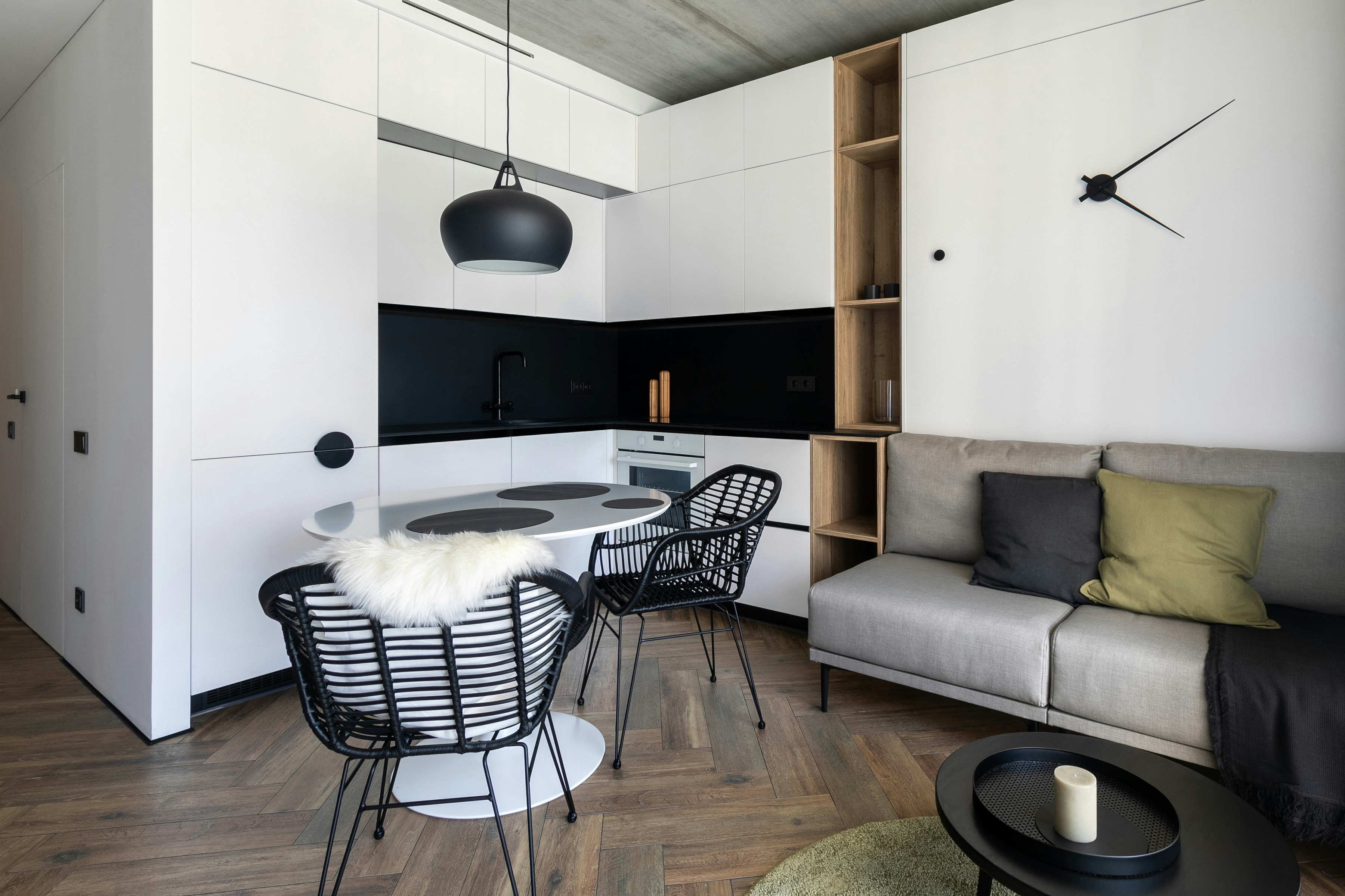 Compact studio apartment with white cabinet wall hiding a corner kitchen beside a lounge