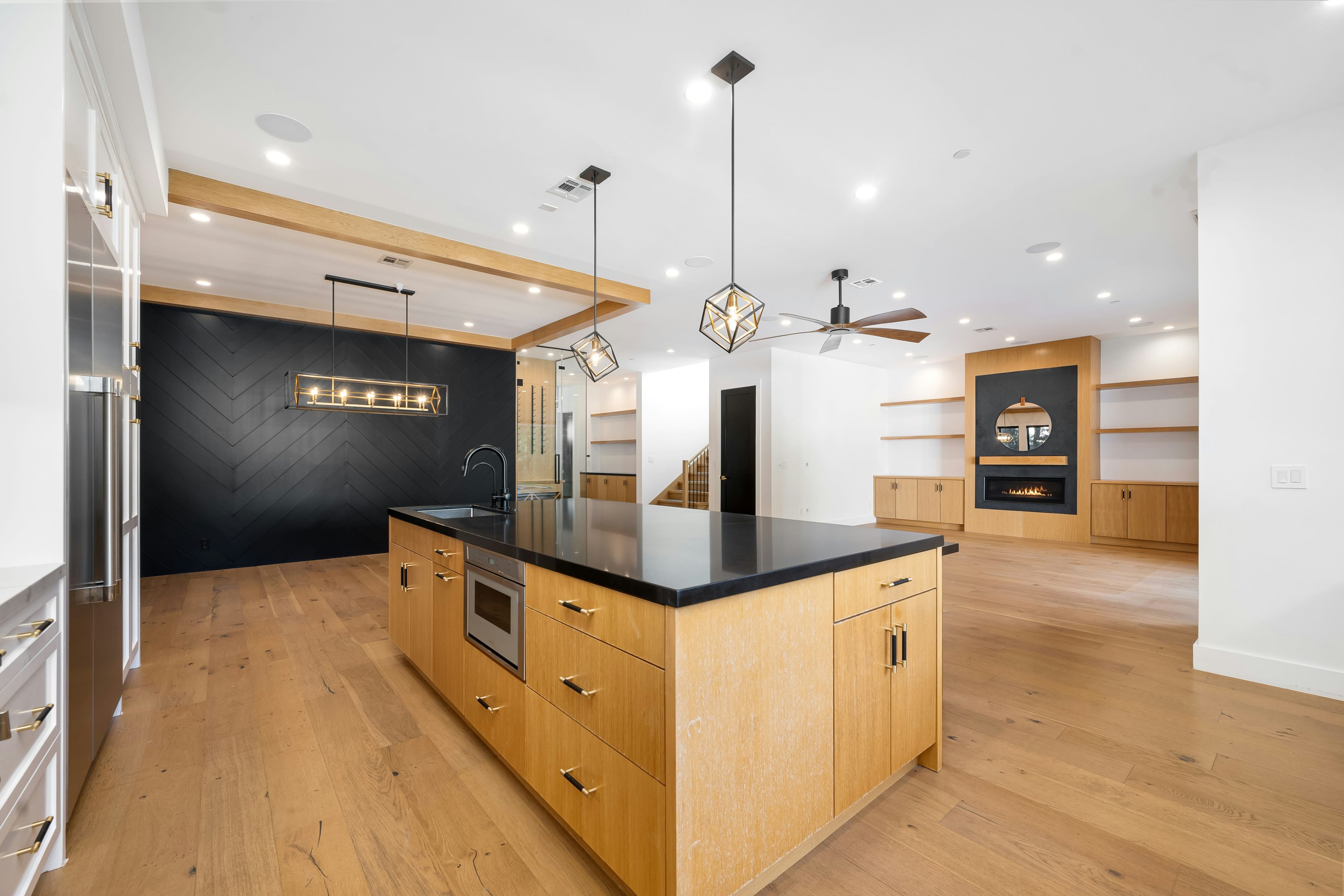 Oak island with black stone look top, black chevron feature wall and wide plank oak floor