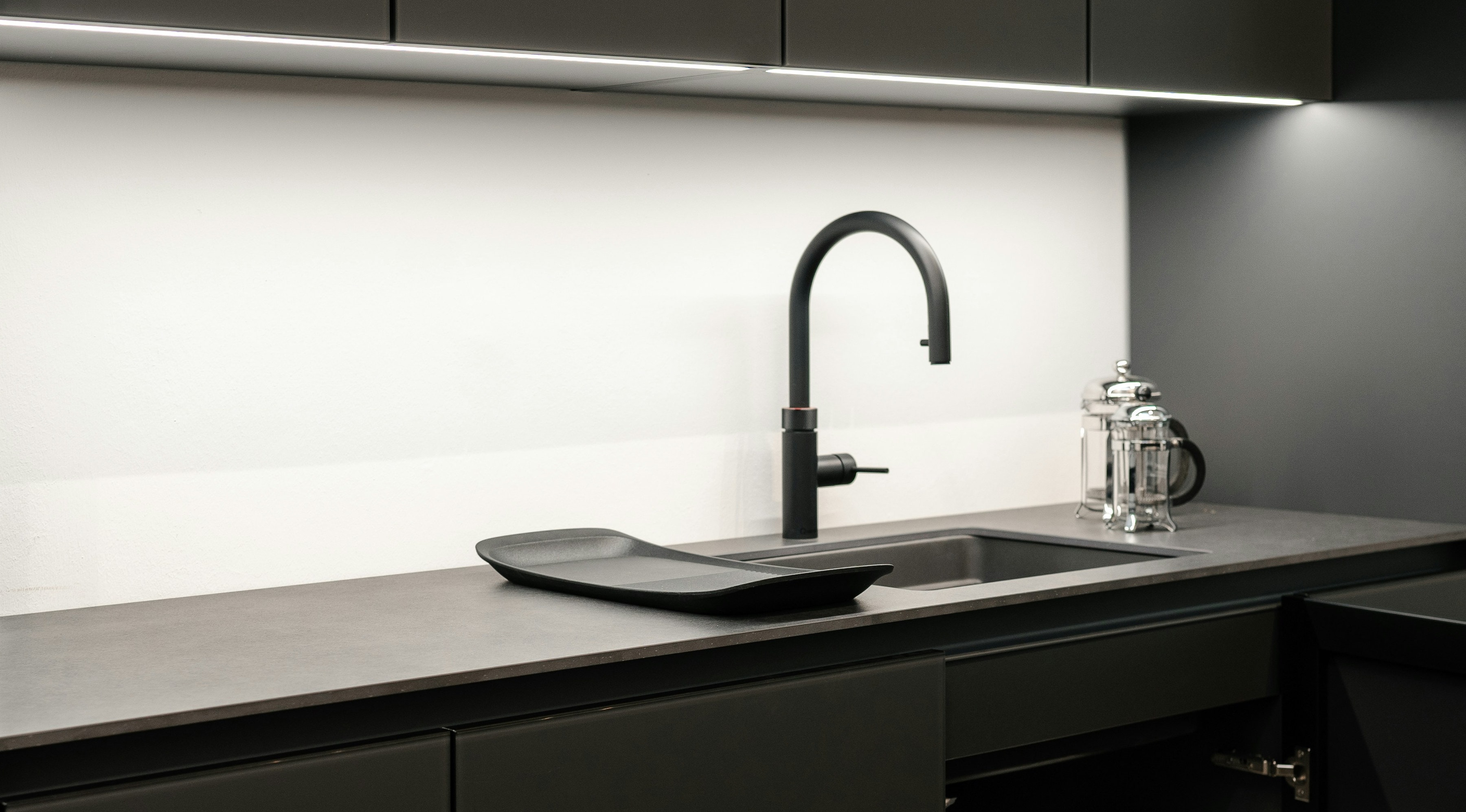 Matt black kitchen with anthracite worktop, black pull tap, undermount sink and LED lit splashback